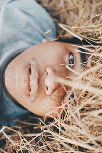 Close-up portrait of young woman lying down in hey