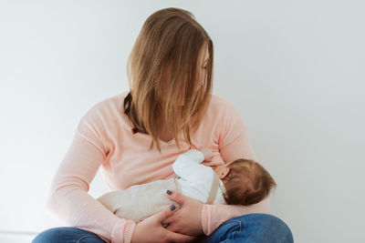 Mother breastfeeding daughter at home