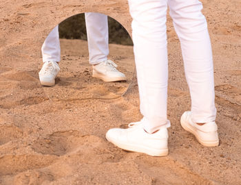 Low section of man standing on sand at beach