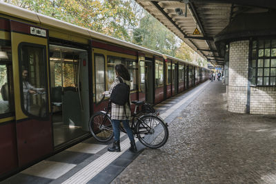 Woman with bicycle entering an underground train, berlin, germany