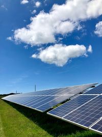 Solar panels on field against sky