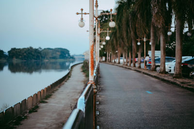 Footpath by river in city against sky