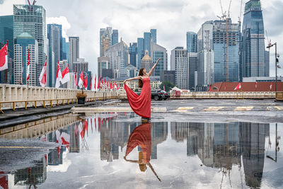 Reflection of woman and buildings on puddle in city