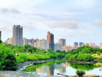 Scenic view of river by buildings against sky