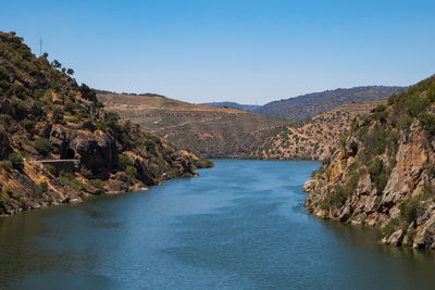 Scenic view of river amidst mountains against clear blue sky