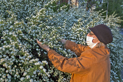 Side view of senior woman holding flowering plants