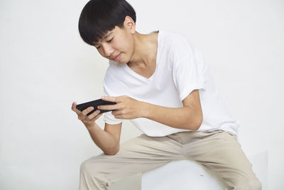 Mid adult man using smart phone against white background