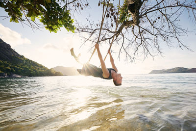 Beautiful sunny day on beach. happy man on swing enjoying holiday in seychelles.