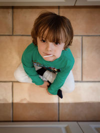 Portrait of cute boy eating lollipop while sitting on floor at home