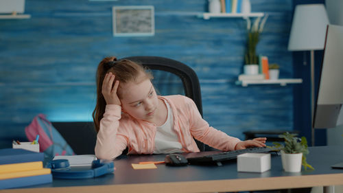 Young woman using mobile phone while sitting on table