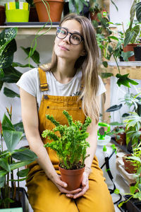 Portrait of woman holding potted plant