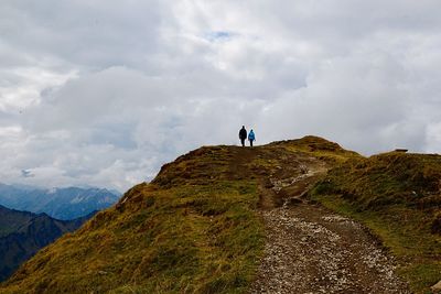 Rear view of hikers walking on mountain against sky