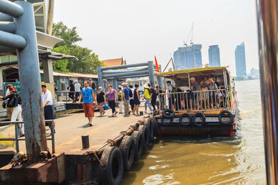 People on boat in sea against buildings