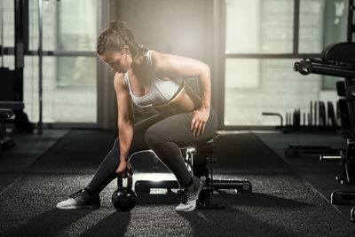 Young woman exercising with kettlebell at gym