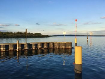 Wooden posts in lake against sky