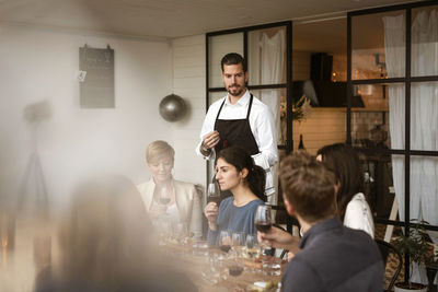 Man wearing apron looking at people tasting wine at workshop