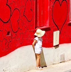 Full length of woman standing against red wall