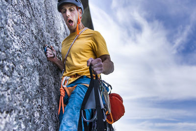 Climber holding portaledge on wall with funny face and open mouth