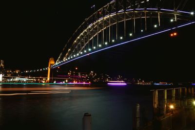 Illuminated bridge over river at night