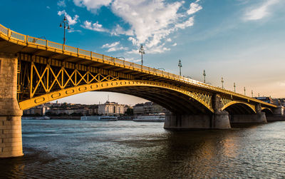 Bridge over river against sky in city