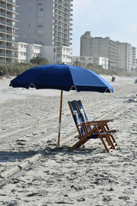 Deck chairs by umbrella on sand