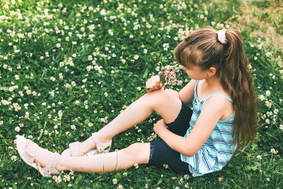 Rear view of girl sitting on field