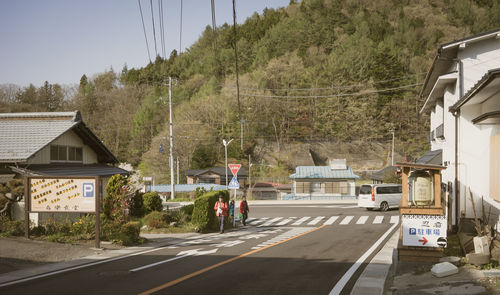 Road amidst trees and buildings against sky