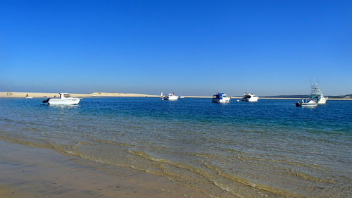 Boats in sea against clear sky