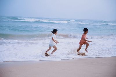 Children running on beach against sea