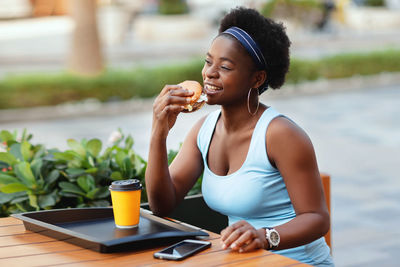 Cute african woman having lunch outdoors in city cafe. an african-american woman smiles