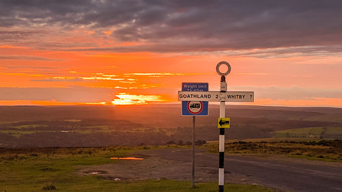 Information sign on road against sky during sunset
