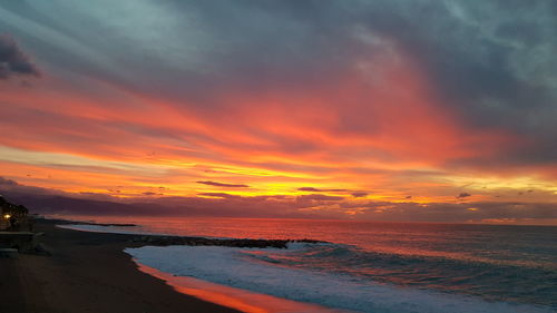 Scenic view of sea against dramatic sky during sunset