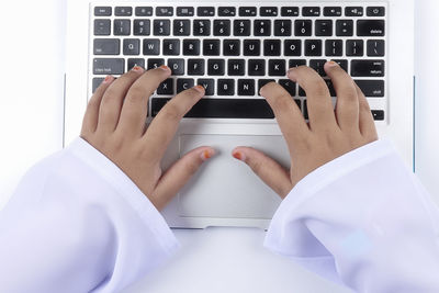 Cropped hands of woman using laptop against white background
