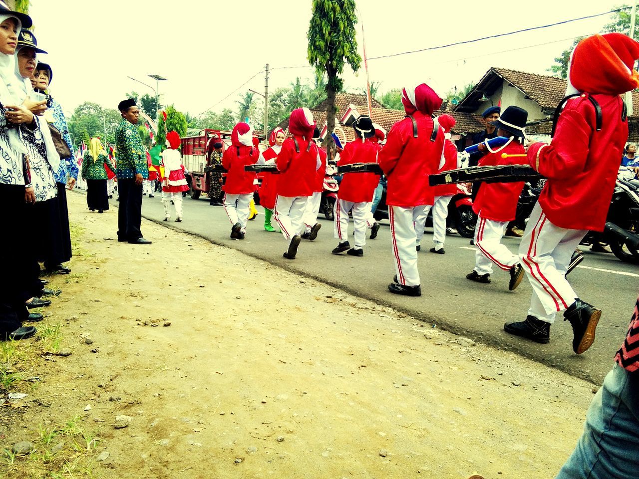 large group of people, full length, celebration, street, in a row, person, tradition, men, lifestyles, leisure activity, religion, cultures, togetherness, red, culture, community, festival, crowd, day, vibrant color, outdoors, celebration event