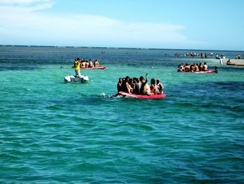 People on boat in sea against sky