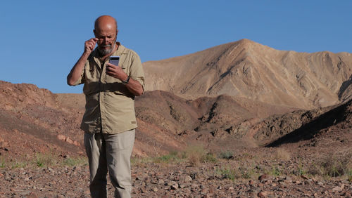 Senior man using smart phone in the desert 