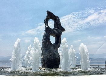 View of fountain in sea against cloudy sky