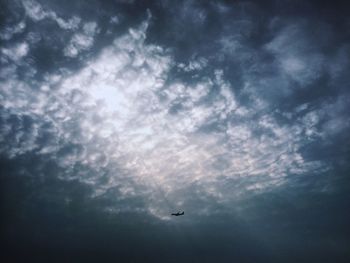 Low angle view of airplane flying against cloudy sky