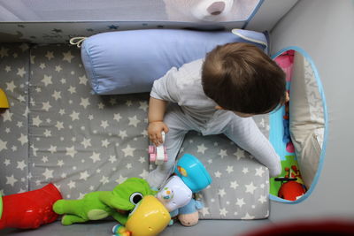 High angle view of boy playing with toys while sitting on sofa at home
