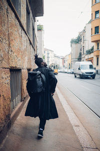 Rear view of man walking on street against buildings