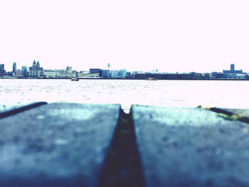 Surface level of river by buildings against clear sky