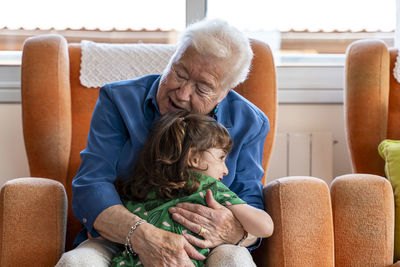 Grandmother hugging her granddaughter in living room