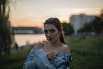 Portrait of young woman standing outdoors during sunset