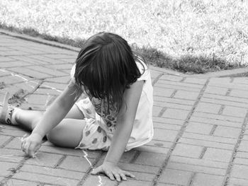 Girl drawing with chalk on footpath