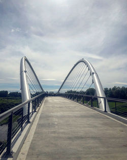 Bridge over road against cloudy sky