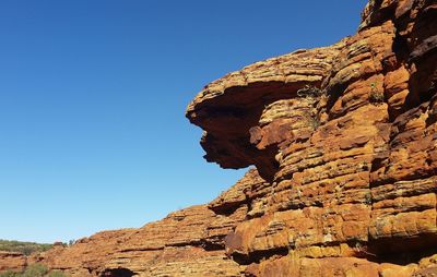 Low angle view of rocky mountain against blue sky