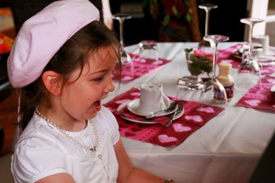 Side view of cheerful girl against elegant dining table