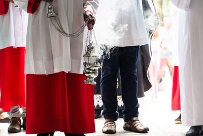 Lower part of catholic church members with incense in the campo santo cemetery 