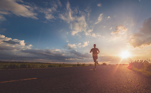 Man standing on road against sky during sunset