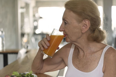 Senior woman drinking juice while siting at home